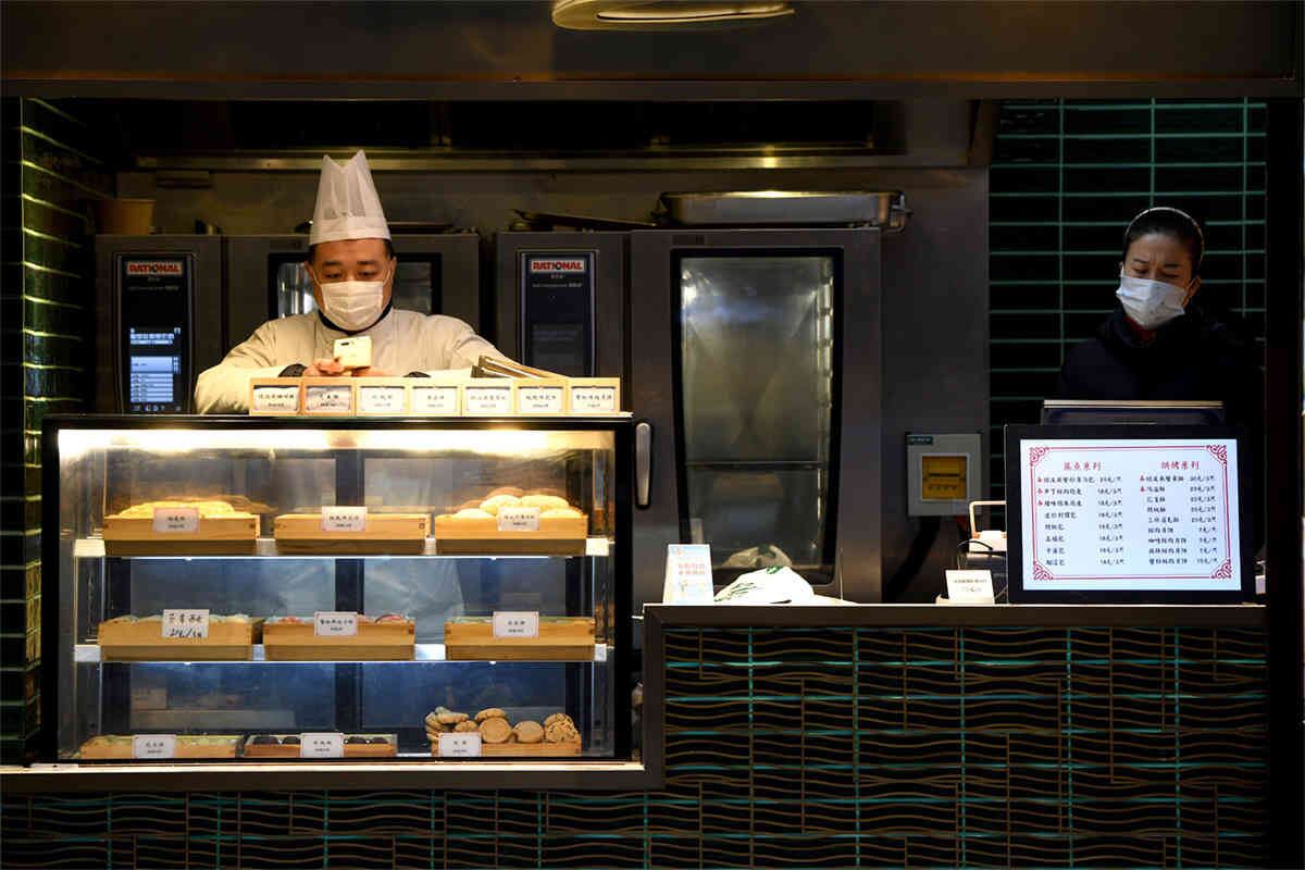 Un cocinero y un vendedor usan máscaras protectoras en Shangai, el 6 de febrero de 2020. El coronavirus ha afectado a más de 28,000 personas en China. Foto: Noel Celis/ AFP. 