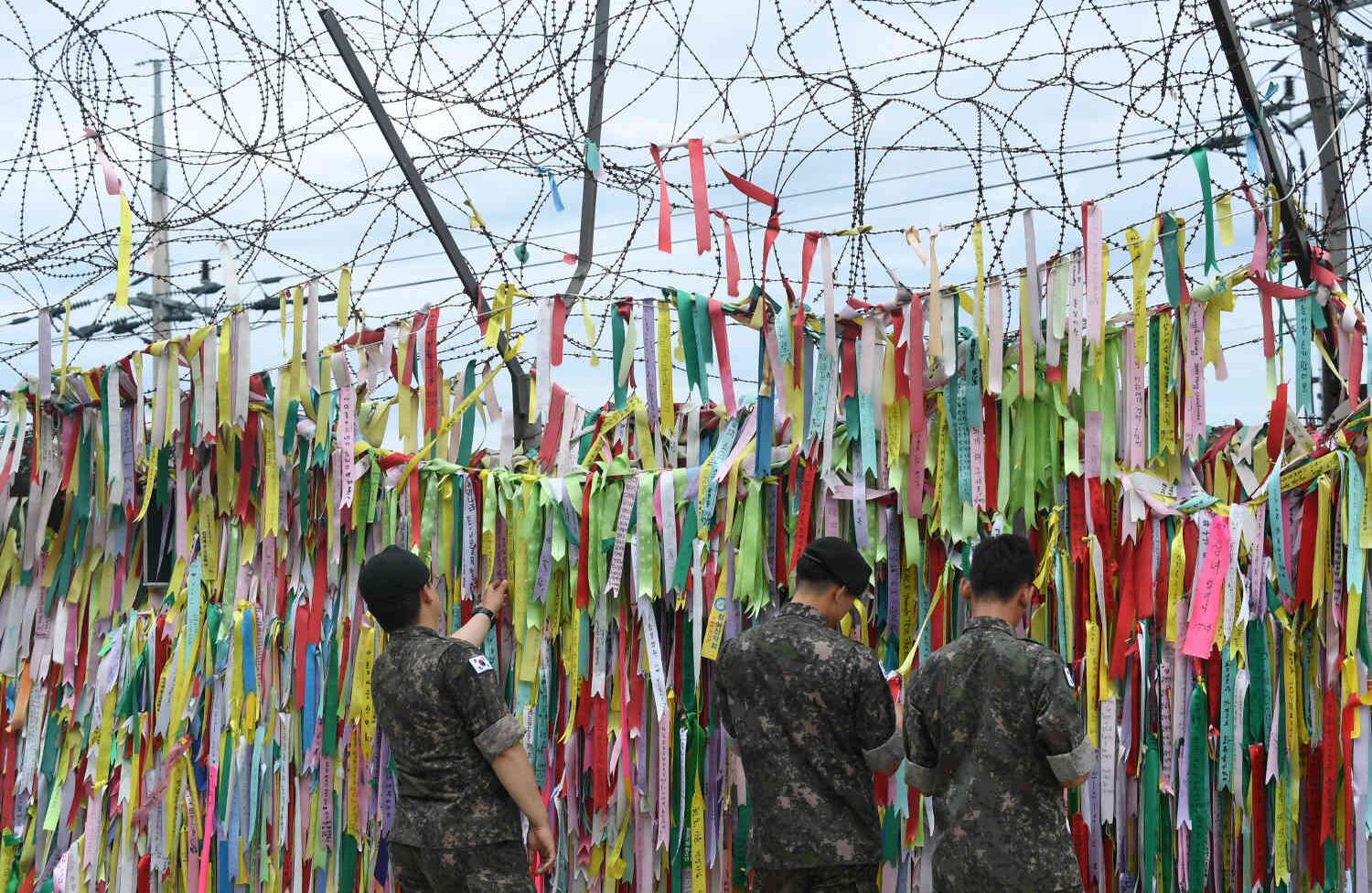 Soldados surcoreanos observan cintas con inscripciones que piden paz y reunificación exhibidas en una valla militar en el parque de paz Imjingak, cerca de la Zona Desmilitarizada (DMZ) que divide a las dos Corea en la ciudad fronteriza de Paju. Jung Yeon-je / AFP