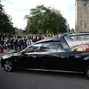 Los miembros del público presentan sus respetos mientras el coche fúnebre que lleva el ataúd de la reina Isabel II, envuelto en el estandarte real de Escocia, pasa por Ballater, el 11 de septiembre de 2022.