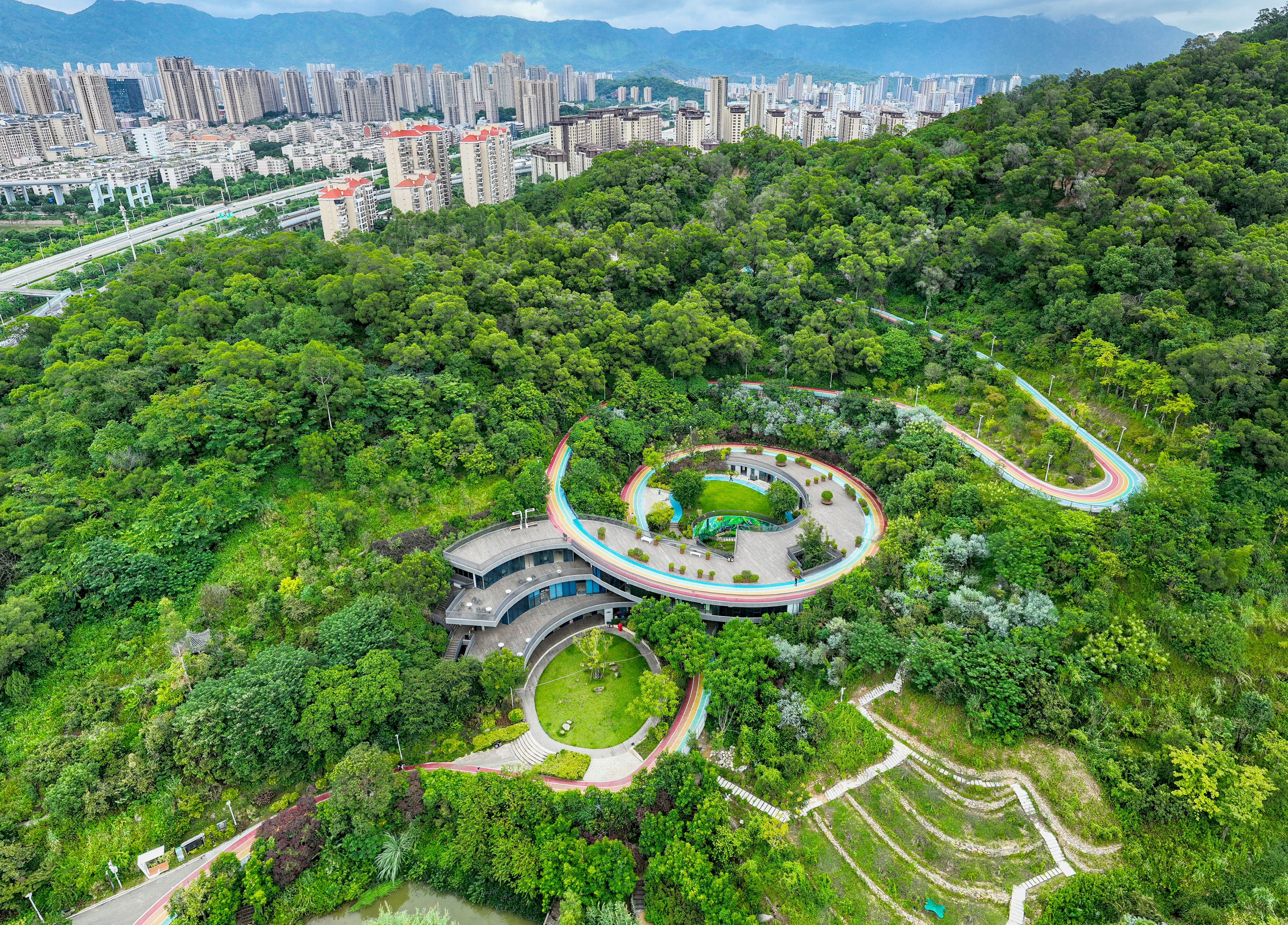 La gente camina a lo largo del Rainbow Walk de la ciudad hacia las verdes montañas en Fushan Country Park, distrito de Gulou, Fuzhou, provincia de Fujian, China