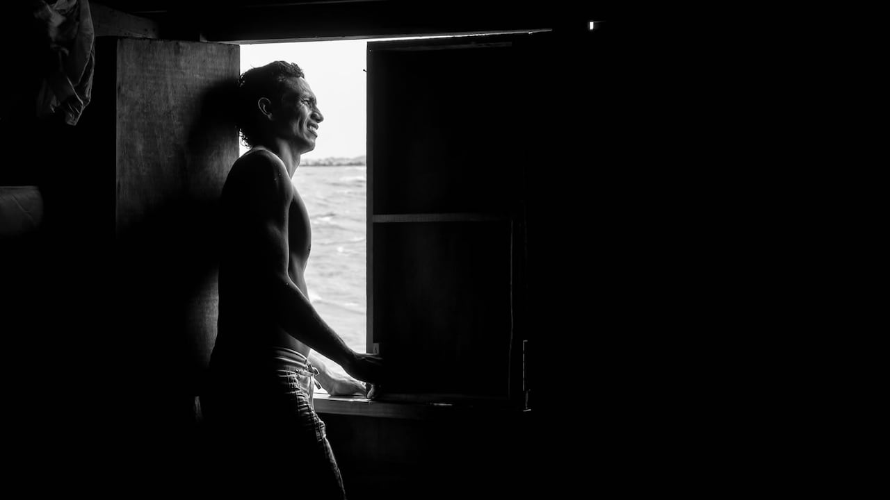 Por la ventana, con vista al río Magdalena, un hombre sale a la luz para mirar al horizonte. Una sonrisa antes de salir a pescar.