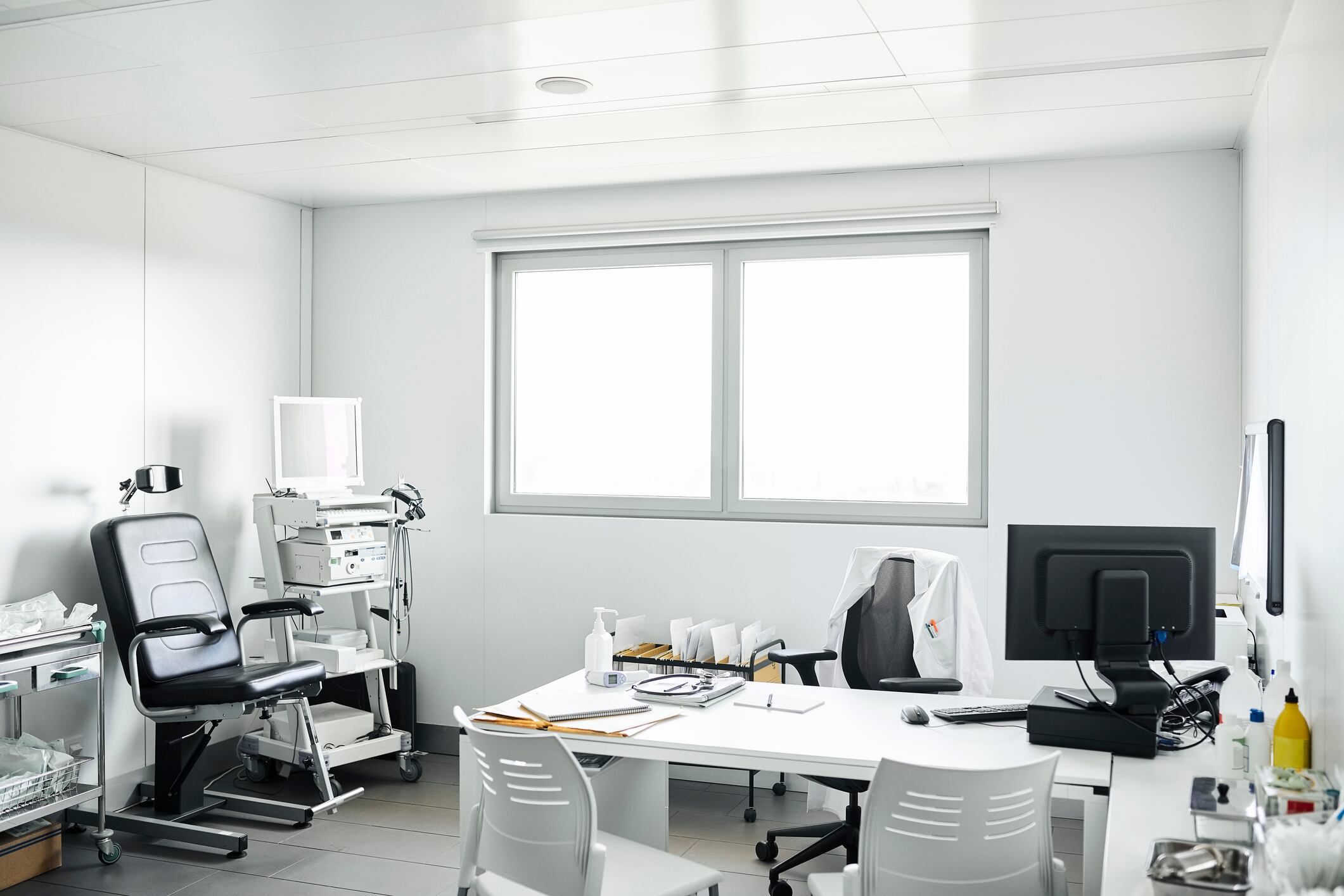 Equipo médico y mobiliario en consultorio médico. Las sillas vacías están en el escritorio de la clínica. Interior de la sala de examen médico en el hospital