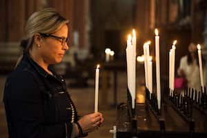 Algunos creyentes prenden velas mientras oran.