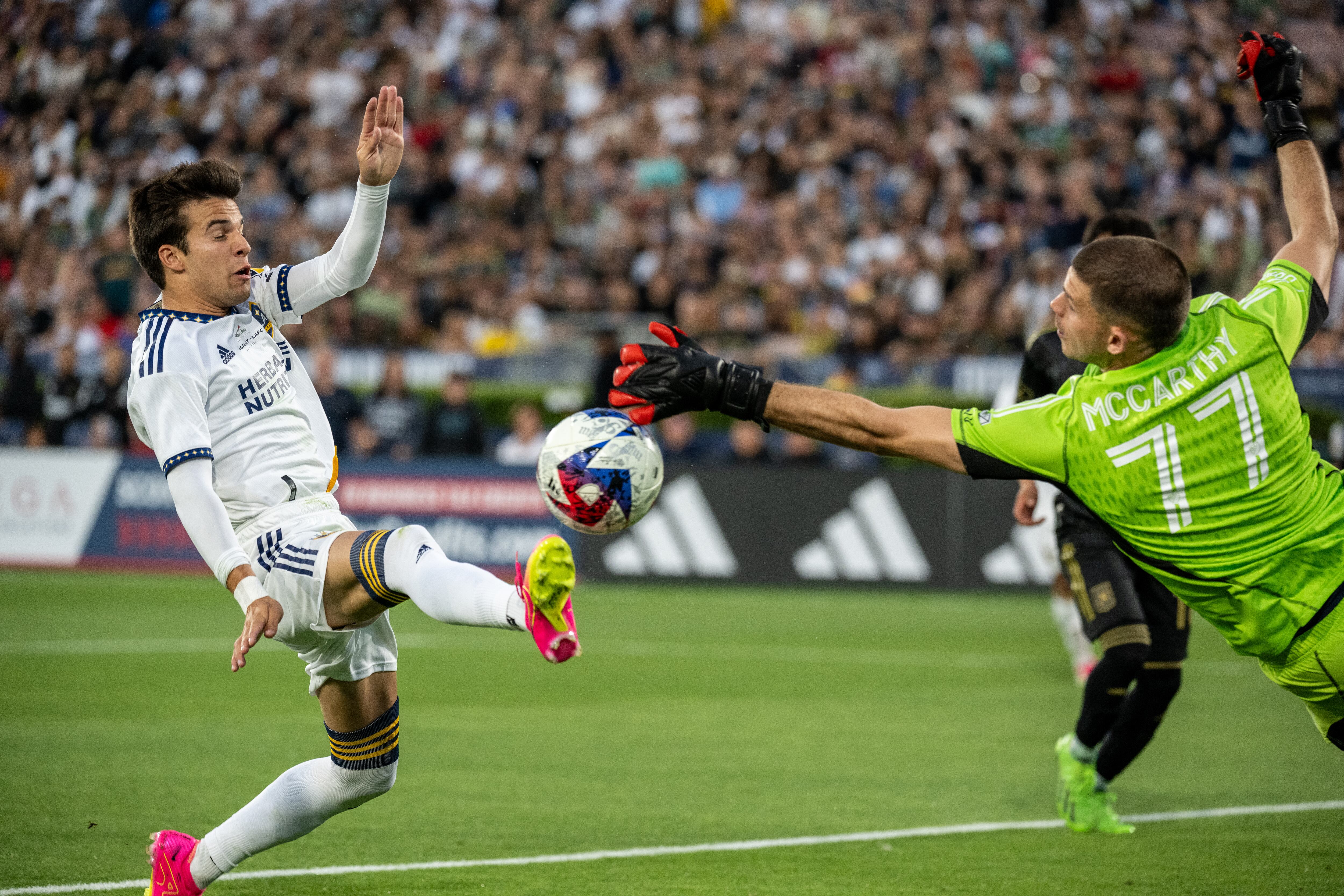PASADENA, CA - 4 DE JULIO: Riqui Puig #6 de Los Angeles Galaxy toma un tiro mientras John McCarthy #77 de Los Angeles FC hace una parada durante el partido entre Los Angeles Galaxy y Los Angeles FC en el Rose Bowl el 4 de julio de 2023 en Pasadena, California. Los Ángeles Galaxy ganó el partido 2-1 (Foto de Shaun Clark/Getty Images)