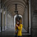 A woman wearing a face mask looks at her mobile under Rua Augusta arcade in Lisbon on October 28, 2020. - The Portuguese support the wearing of the compulsory mask outdoors, a measure that came into force today, in order to stem the resumption of the coronavirus epidemic. (Photo by PATRICIA DE MELO MOREIRA / AFP)