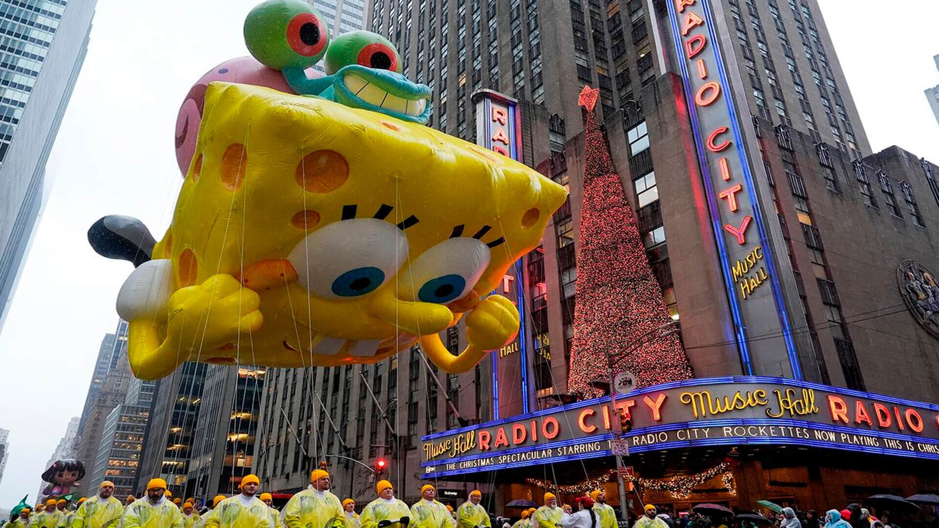 Los manipuladores guían el globo de Bob Esponja por la Sexta Avenida durante el Desfile del Día de Acción de Gracias
