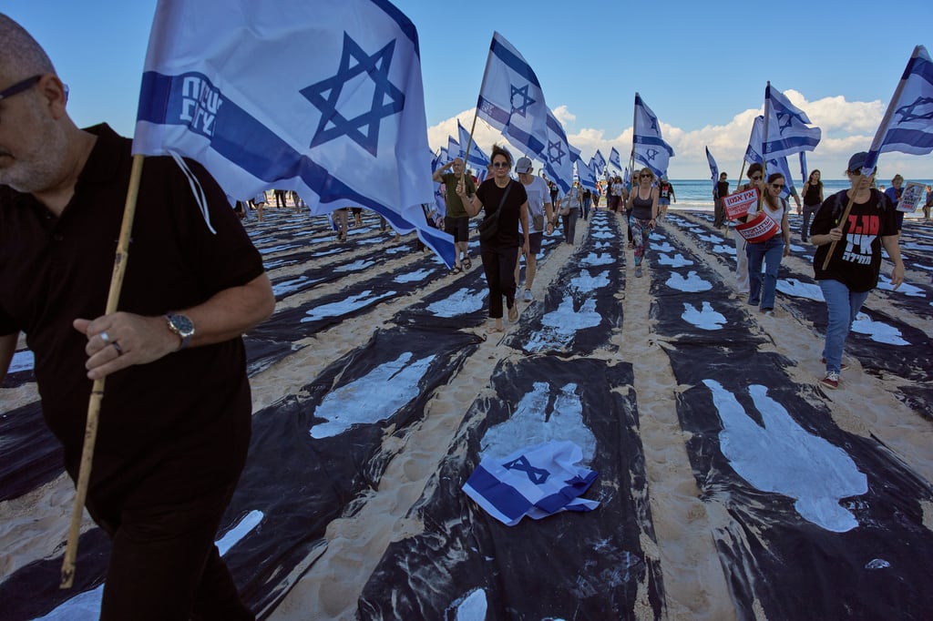 Personas que portan banderas de Israel caminan por una instalación que conmemora el tercer aniversario del ataque de Hamás a Israel del 7 de octubre de 2023