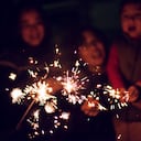 A child is playing sparklers with his family at night