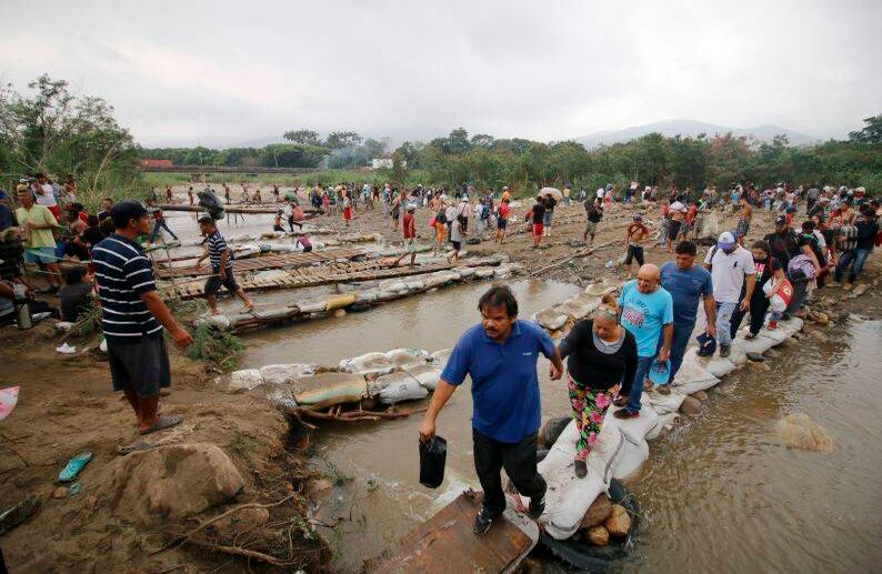 La gente cruza el río Táchira hacia Colombia utilizando puentes improvisados a medida que el nivel del agua crece a medida que se acerca la temporada de lluvias. FOTO: Schneyder Mendoza/AP