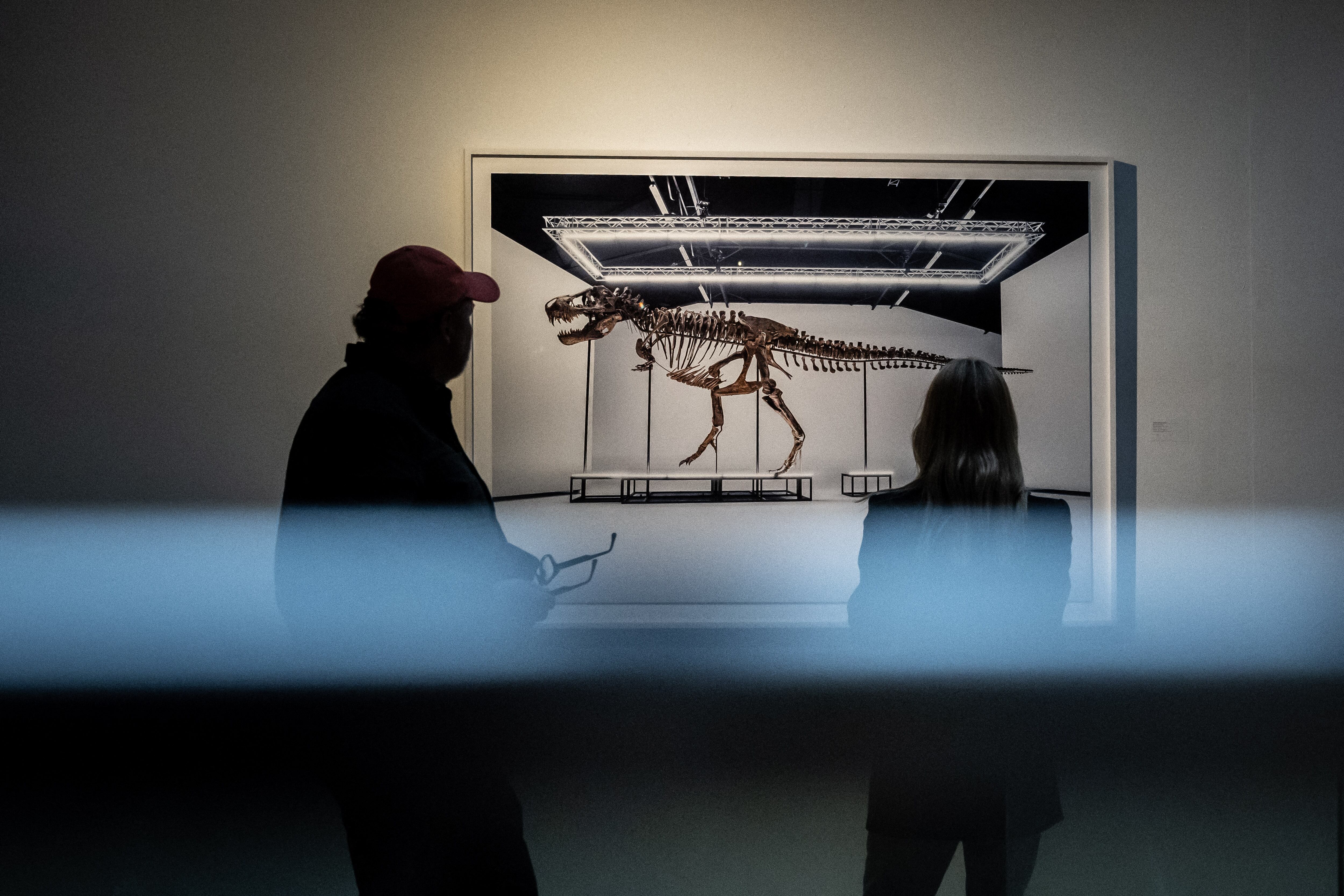 Los postores se ven junto a una imagen de 'Trinity' después de la venta del esqueleto Tyrannosaurus-Rex (T-Rex) por parte de la casa de subastas Koller en Zúrich, el 18 de abril de 2023