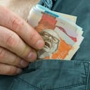 the man takes a bundle of columbian pesos from his shirt pocket