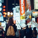 Joven viajera asiática explorando y paseando por la concurrida y colorida calle del centro de la ciudad con letreros de neón por la noche en Osaka, Japón.
