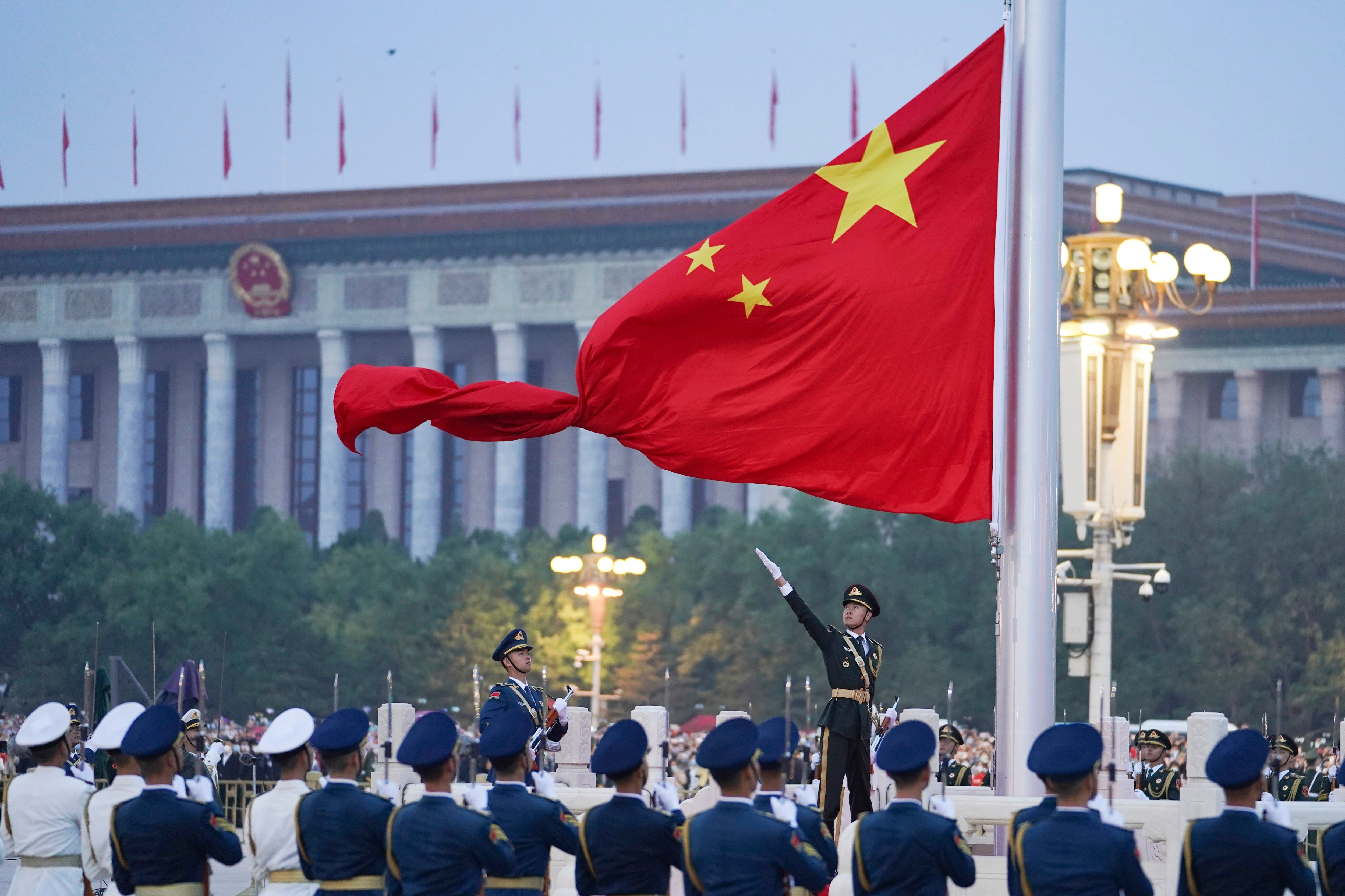 Un soldado de la guardia de honor desplega la bandera china durante una ceremonia en el 73er aniversario de la fundación de la República Popular China en la Plaza Tienanmen, Beijing