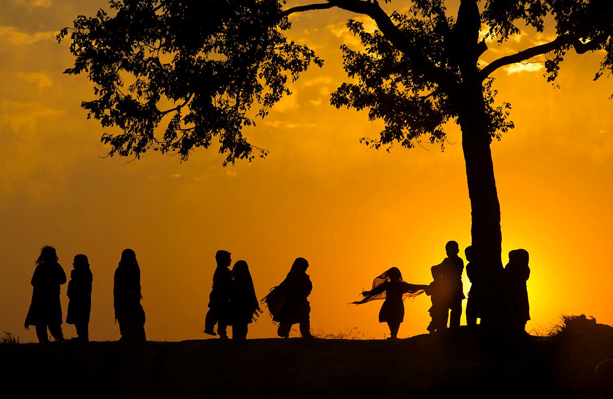 En Pakistán, niños desplazados por la violencia juegan bajo un árbol durante el último atardecer del 2014, en las afueras de Islamabad. (AP) 