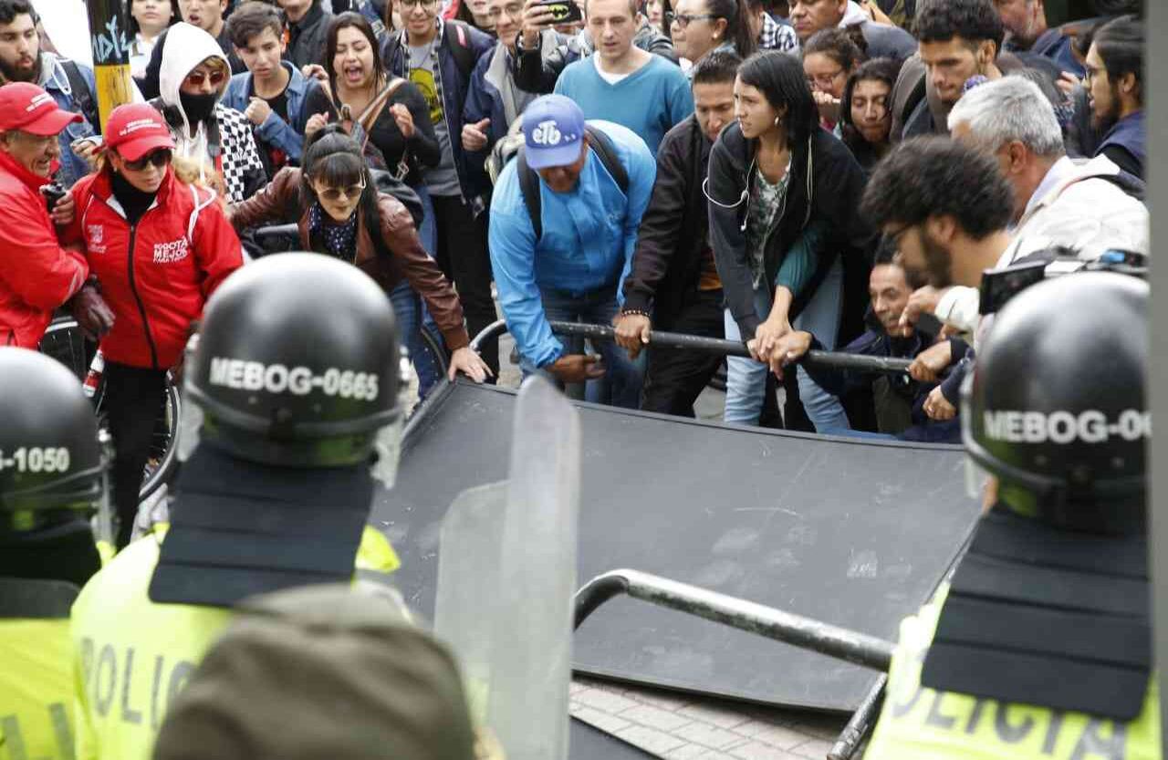 Los antiuribistas intentaron saltar las vallas de la Policía para protestar frente al Palacio de Justicia. Foto: Guillermo Torres Reina