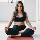 Mujer adulta joven está practicando yoga en un loft moderno. Postura de medio loto o ardha padmasana.