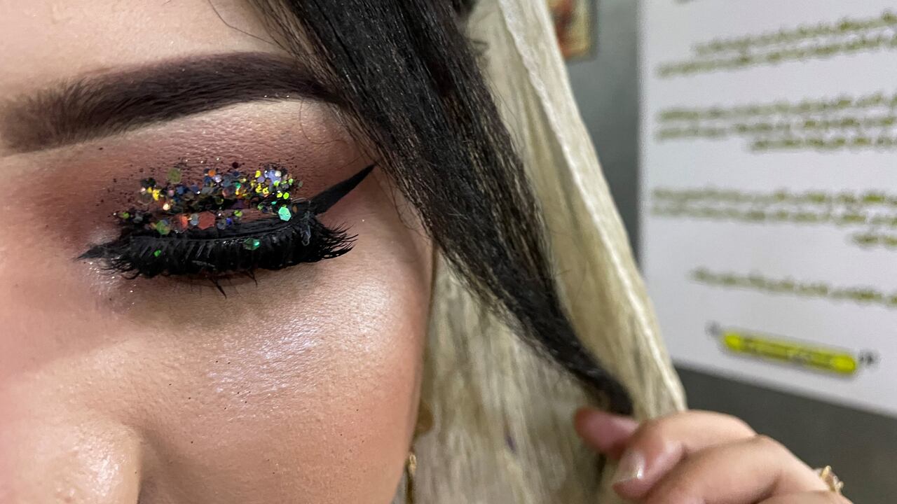 Una clienta muestra su maquillaje realizado por una esteticista en un salón de belleza en Kabul. - Es uno de los últimos lugares en Kabul donde las mujeres pueden encontrarse fuera de sus hogares, una burbuja de libertad e incluso frivolidad lejos de la mirada de los hombres. (Foto de Maryke Vermaak / AFP)