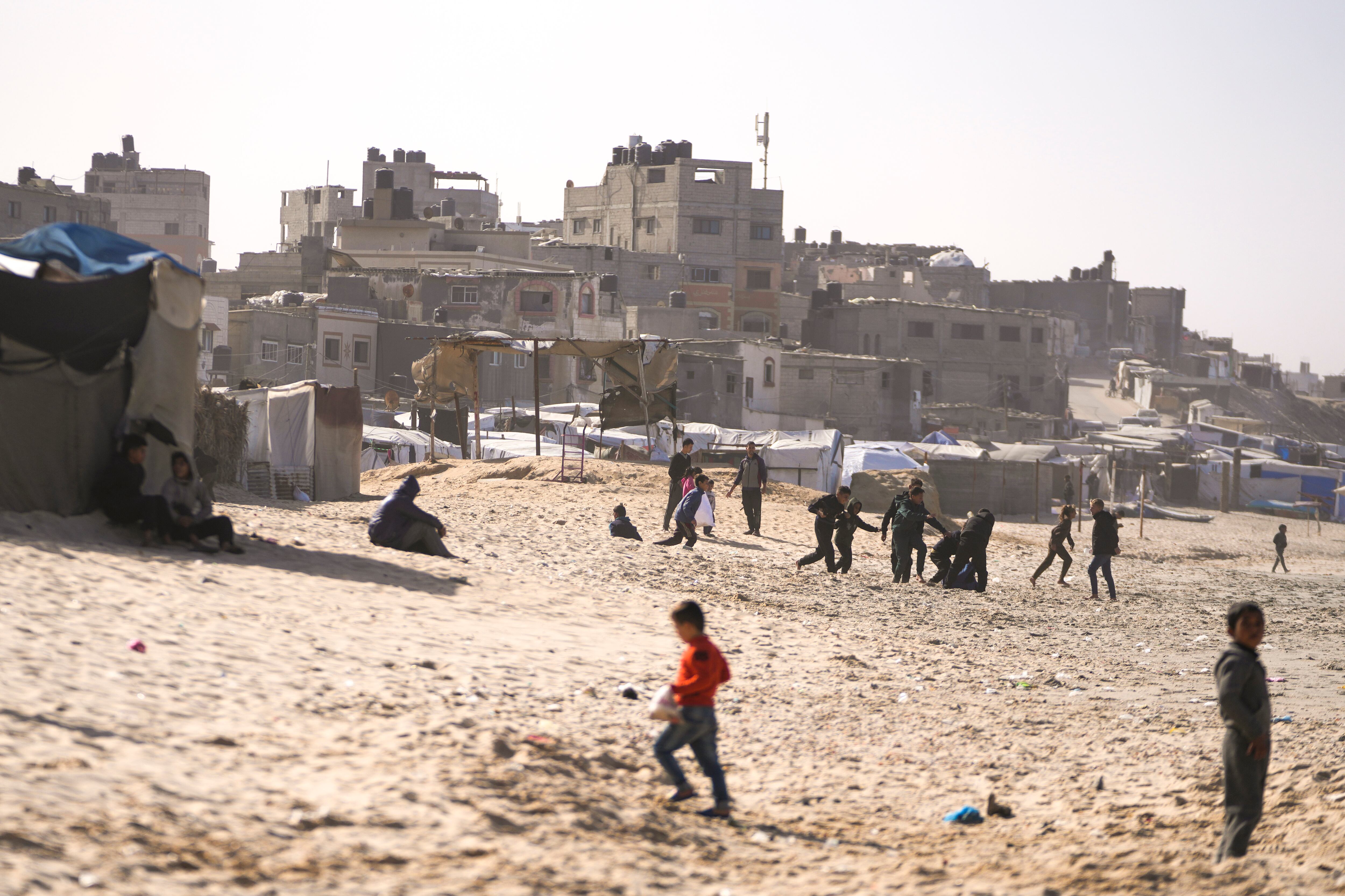 Niños juegan en la arena en un campamento para palestinos desplazados internos frente a la playa en Deir al-Balah, en el centro de la Franja de Gaza