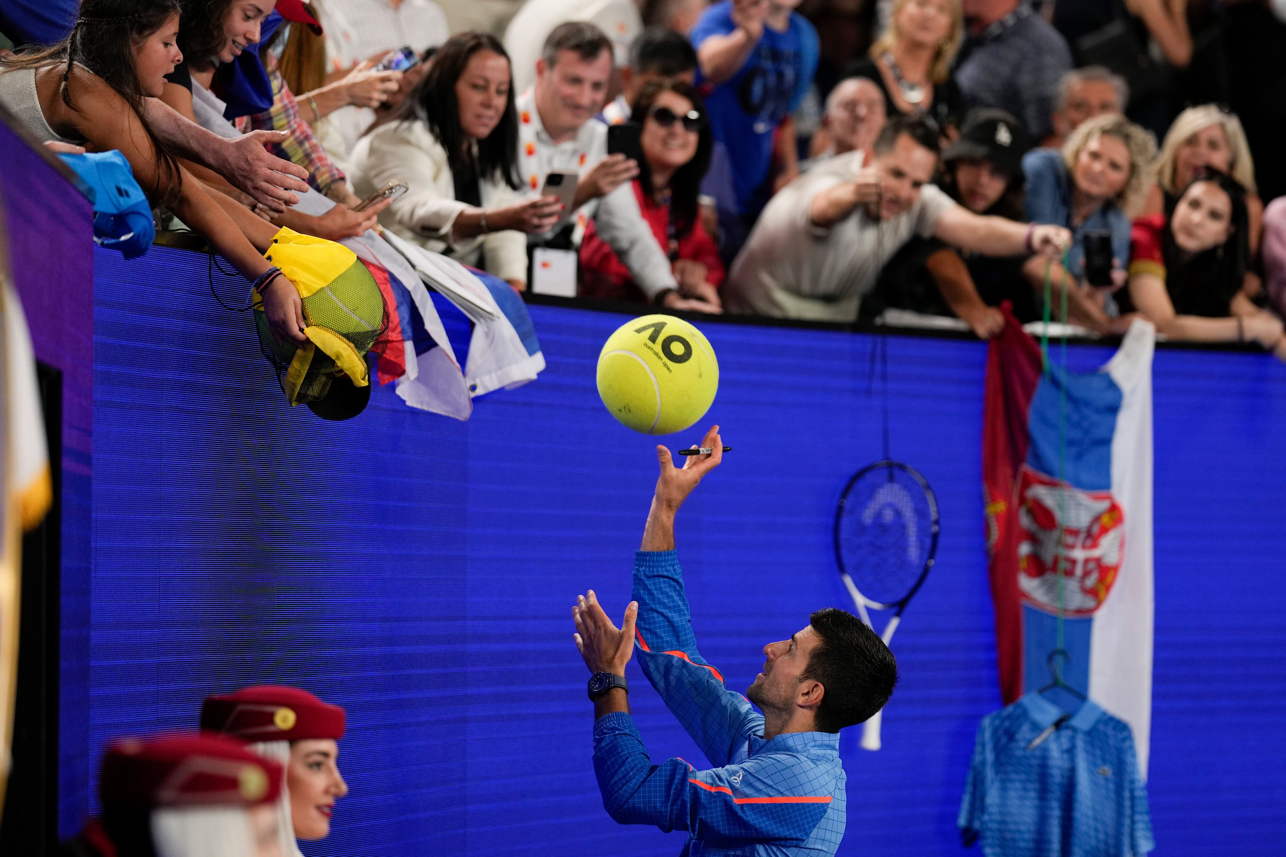 Novak Djokovic of Serbia signs autographs for fans following his fourth round match against Alex de Minaur of Australia at the Australian Open tennis championship in Melbourne, Australia, Monday, Jan. 23, 2023. (AP Photo/Ng Han Guan)