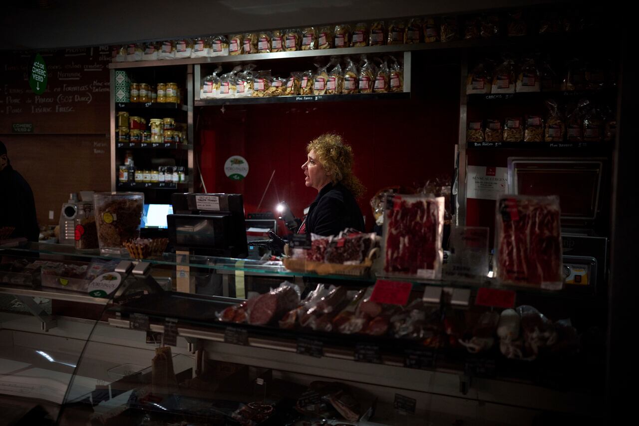 Vendedores utilizan la luz de sus celulares para elegir comida durante un apagón generalizado, el lunes 28 de abril de 2025, en Barcelona. (AP Foto/Emilio Morenatti)