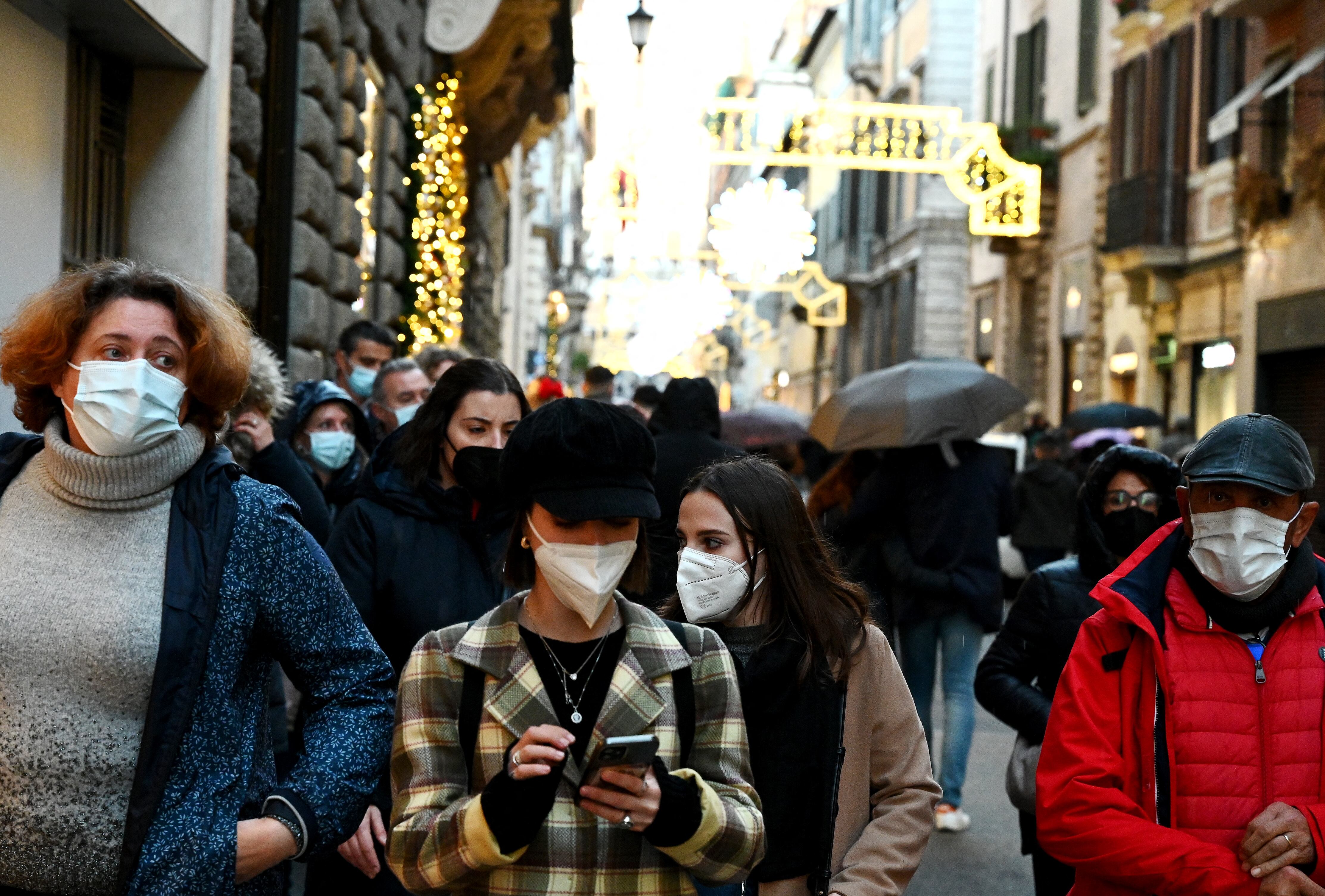 Las personas usan máscaras protectoras mientras caminan por la calle comercial de lujo Via Condotti en el centro de Roma el 5 de diciembre de 2021, ya que la ciudad impuso la obligación hasta el 31 de diciembre de usar máscaras al aire libre en el centro de la ciudad y otras áreas comerciales concurridas, en un intento por reducir el riesgo de infecciones por covid entre la multitud de personas durante la temporada navideña. (Foto de Vincenzo PINTO / AFP)