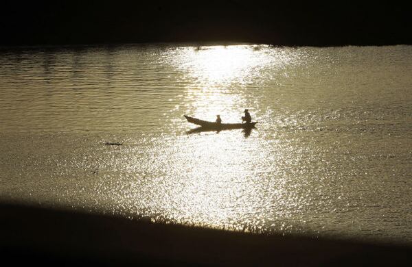 Dos personas cruzan el río Buriganga en las afueras de la ciudad de Daca, capital de Bangladés, en Asia. (AP) 
