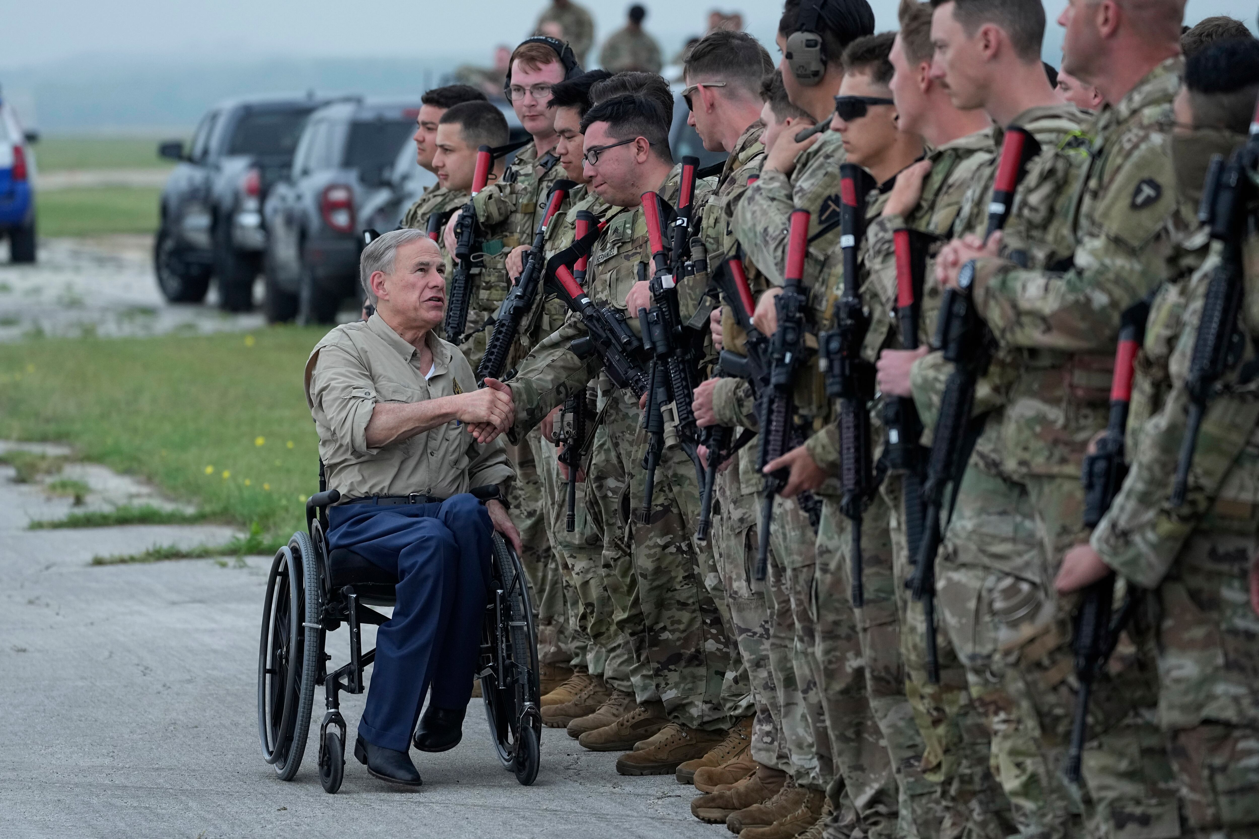 El gobernador de Texas, Greg Abbott, a la izquierda, le da la mano a miembros de la Guardia Nacional de Texas mientras se preparan para desplegarse en la frontera entre Texas y México en Austin, Texas