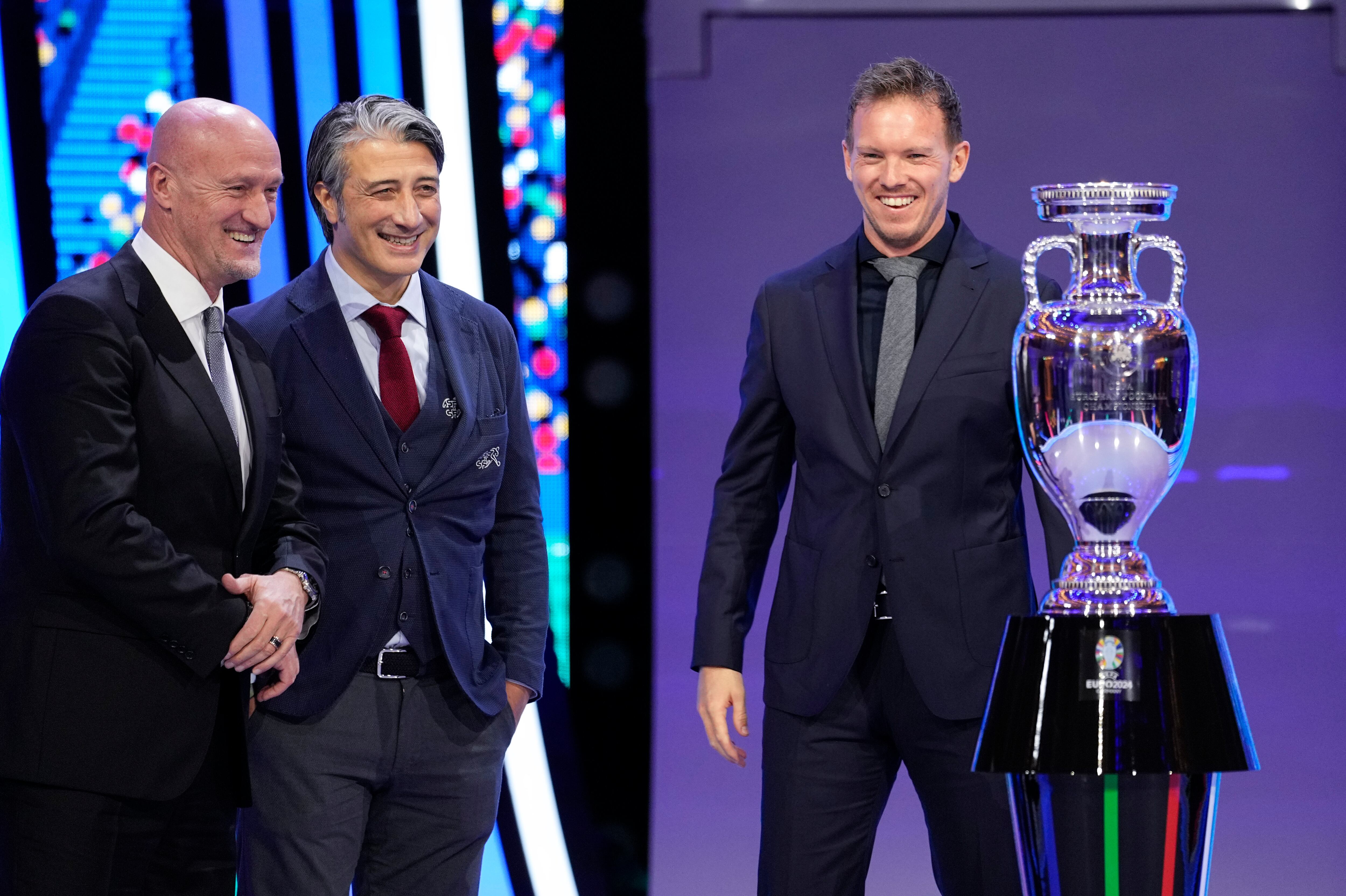 Los entrenadores en jefe de Hungría Marco Rossi, izquierda, Suiza Murat Yakin, centro, y Alemania Julian Nagelsmann, derecha, posan junto al trofeo después del sorteo de la final del torneo de fútbol UEFA Euro 2024 en Hamburgo, Alemania, el sábado 2 de diciembre. 2023. (Foto AP/Martin Meissner)