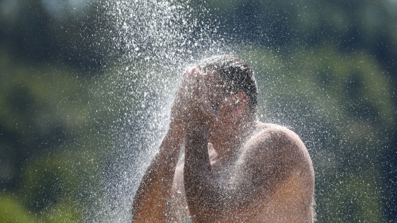25 de junio de 2023, Baden-Württemberg, Ertingen: Un hombre se refresca bajo una ducha en Schwarzachtalsee