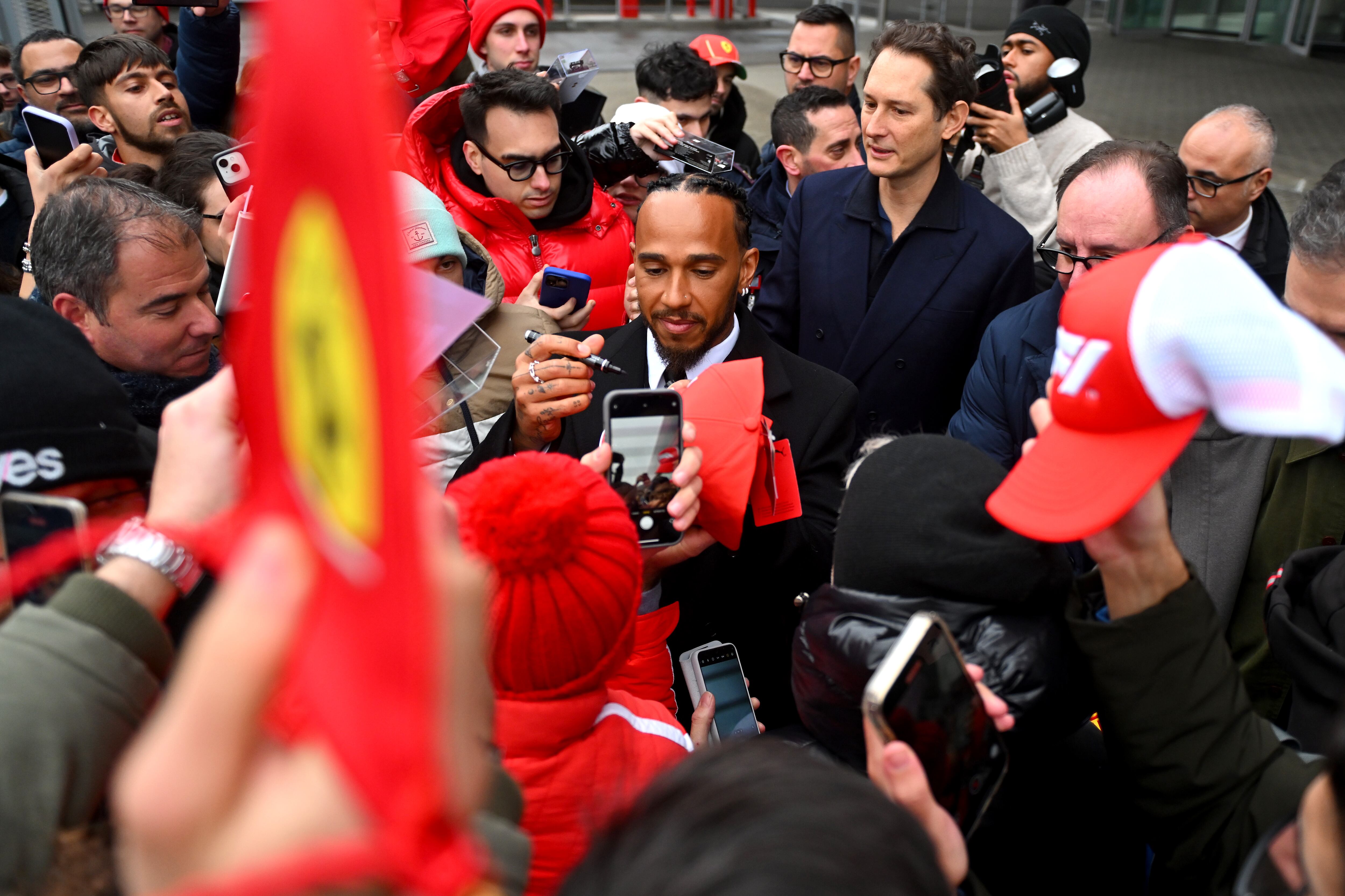 Sir Lewis Hamilton saluda a los aficionados durante sus primeros días oficiales como piloto de F1 de la Scuderia Ferrari en el Circuito de Fiorano mientras John Elkann, CEO de Exor, observa, el 20 de enero de 2025 en Fiorano Modenese, Italia.