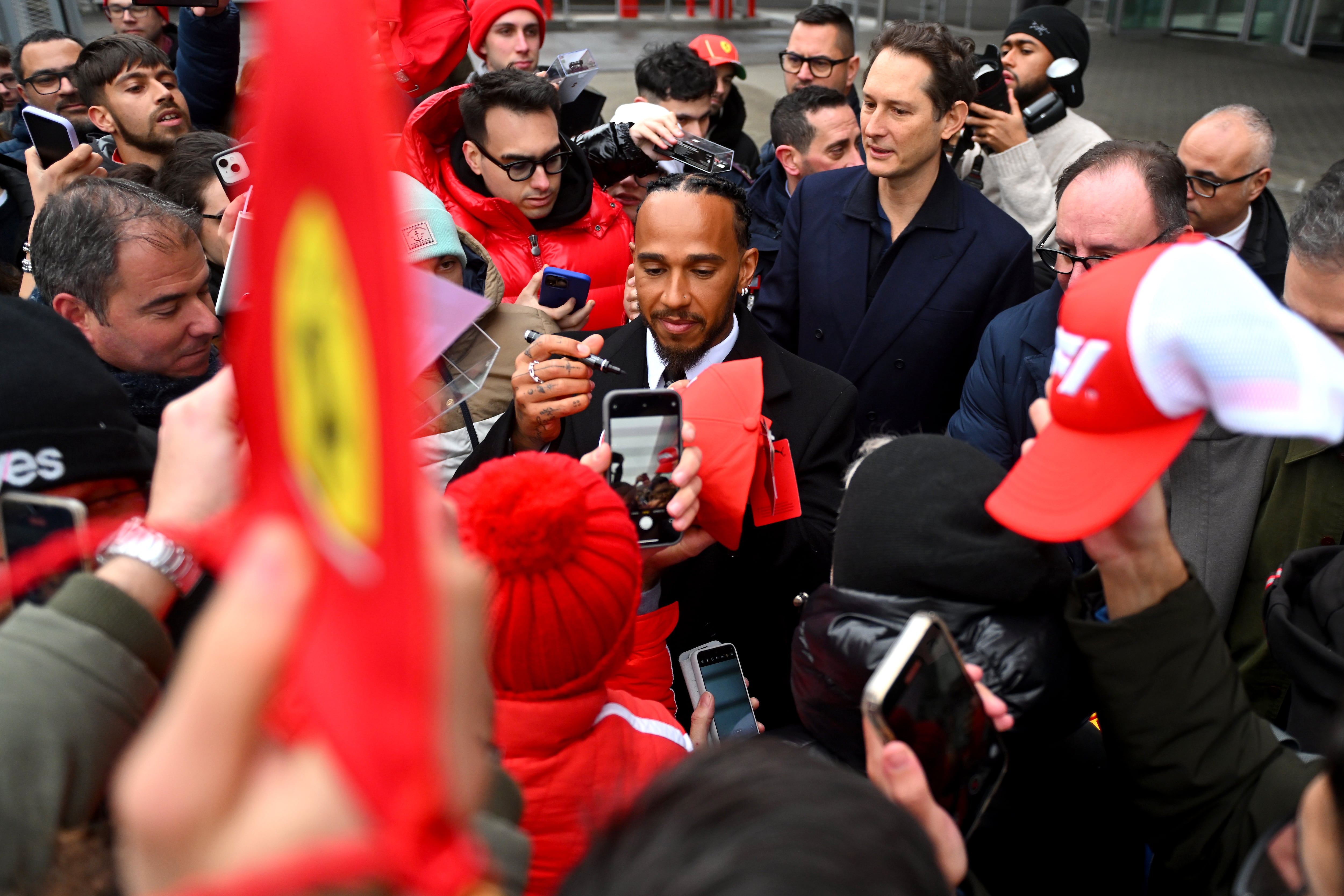 Sir Lewis Hamilton saluda a los aficionados durante sus primeros días oficiales como piloto de F1 de la Scuderia Ferrari en el Circuito de Fiorano mientras John Elkann, CEO de Exor, observa, el 20 de enero de 2025 en Fiorano Modenese, Italia.