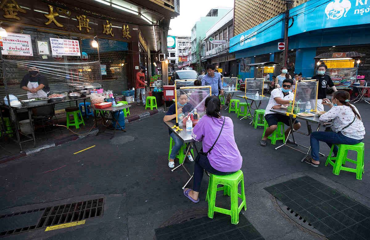  Tailandeses disfrutan de la comida rápida, detrás de láminas de plástico, para ayudar a frenar la propagación del coronavirus en Bangkok, el 12 de mayo. Los pequeños restaurantes son uno de los pocos negocios a los que se les ha permitido abrir durante el relajamiento de las restricciones en la capital tailandesa. Foto: Sakchai Lalit/ AP. 