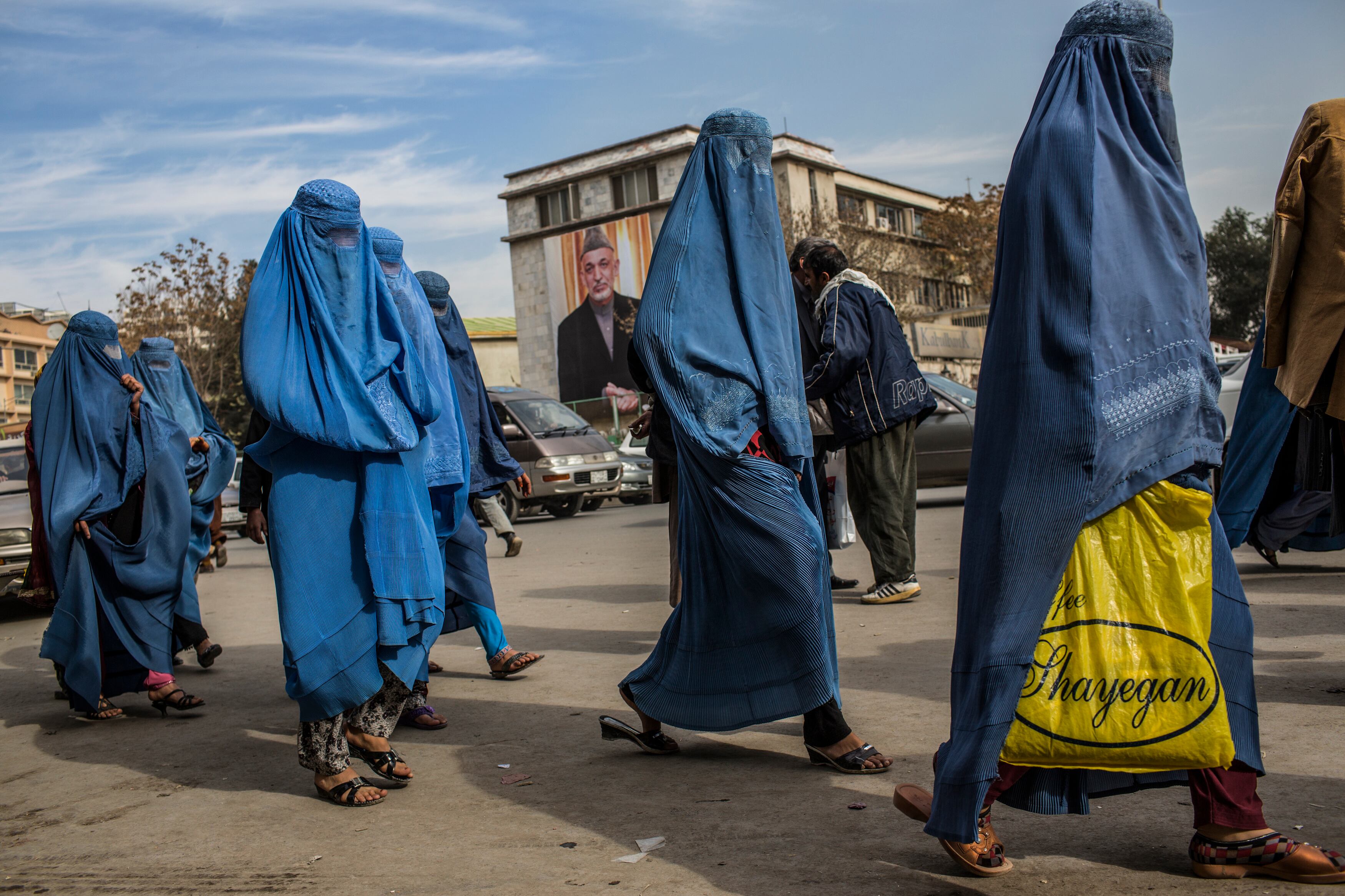 KABUL, AFGHANISTAN - NOVEMBER 07:  Afghan women walk through the street, as a poster of President Hamid Karzai is seen on the outside City Hall on November 7, 2012 in Kabul, Afghanistan. (Photo by Daniel Berehulak/Getty Images)