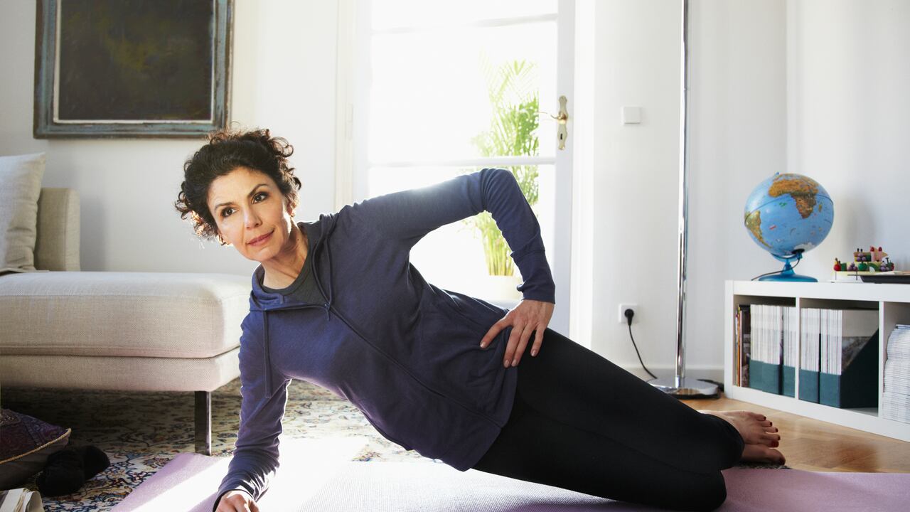Mujer adulta media haciendo yoga en casa