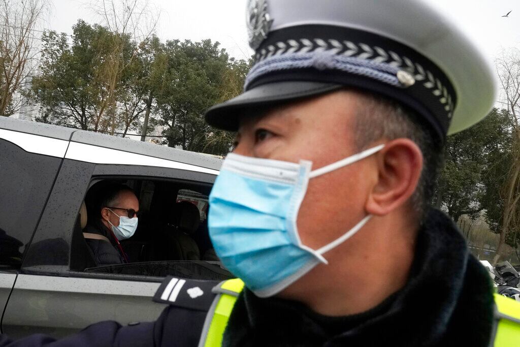 Peter Ben Embarek. del equipo de la Organización Mundial de la Salud, pasa junto a un policía chino a su salida en una caravana del mercado de alimentación de Baishazhou, en el tercer día de visitas sobre el terreno en Wuhan, en la provincia china de Hubei.