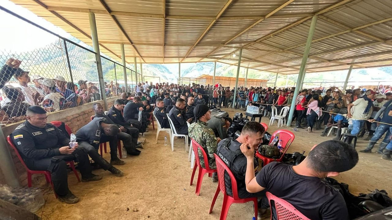 Los uniformados están sentados en sillas mientras que son observados por un gran número de personas.