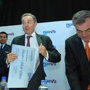 El expresidente Álvaro Uribe intenta guardar el carné (simbólico) 001 de ‘Nueva EPS’, que le fue entregado durante la presentación de la nueva entidad, que reemplaza a la EPS del ISS. Lo observan el expresidente de Nueva EPS, Héctor Cadena, y el exministro de la Protección Social, Diego Palacio Betancourt. Foto: César Carrión