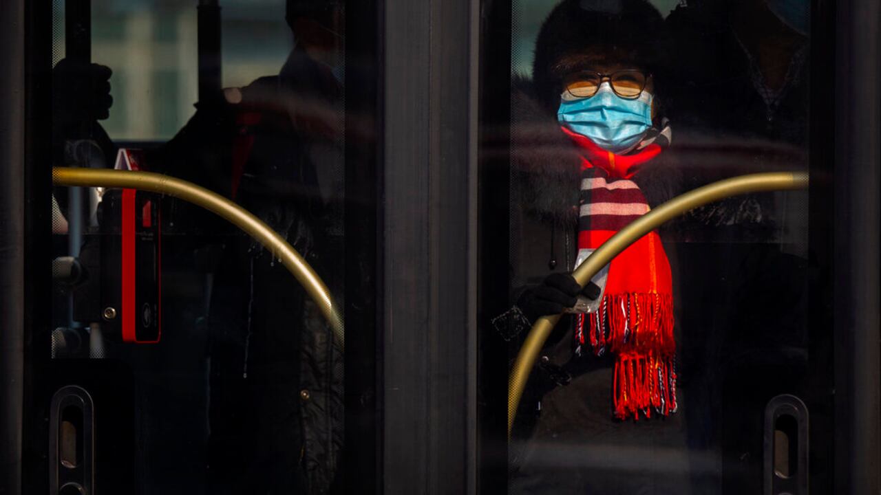 A woman wearing a face mask to protect against the spread of the coronavirus rides a public bus in Beijing, Wednesday, Jan. 20, 2021. China is now dealing with coronavirus outbreaks across its frigid northeast, prompting additional lockdowns and travel bans. (AP Photo/Mark Schiefelbein)