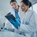 Laboratorio de Investigación Médica Moderna: Dos Científicas Trabajando, Usando Tableta Digital, Analizando Muestras, Hablando. Laboratorio Farmacéutico Científico Avanzado para Medicina, Desarrollo de Biotecnología