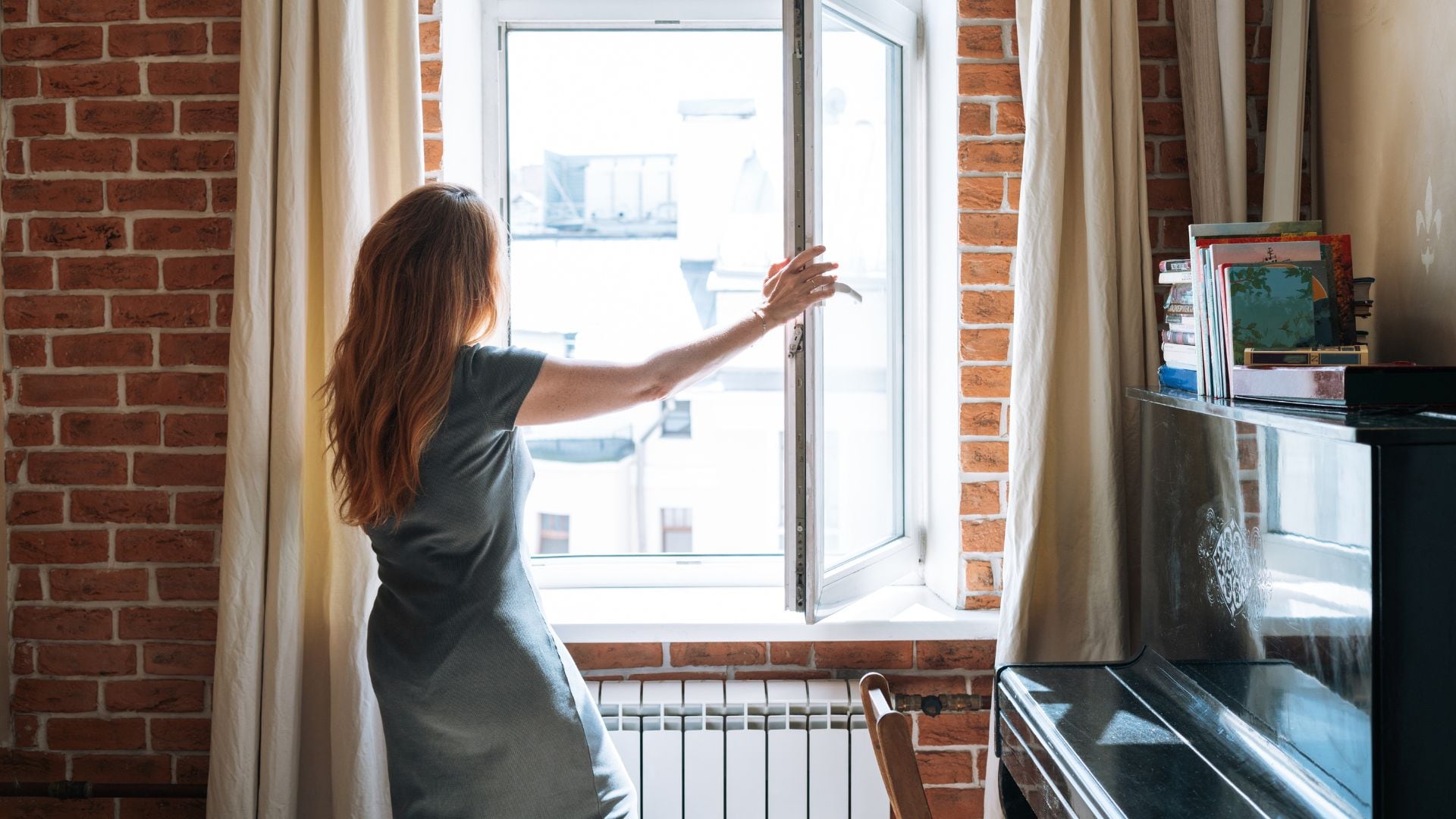 Imagen de referencia de mujer abriendo la ventana de su casa.