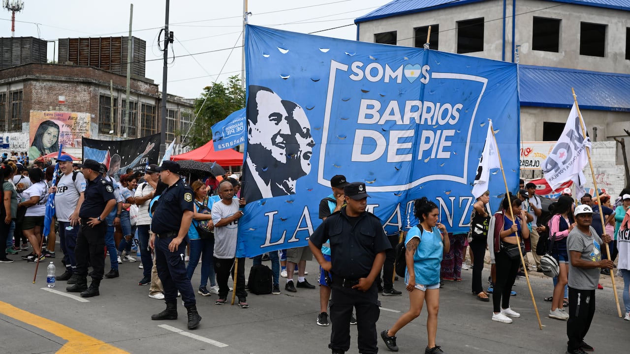 Oficiales de policía hacen guardia en una calle mientras miembros de organizaciones sociales protestan contra el decreto de emergencia del presidente argentino Javier Milei en La Matanza, provincia de Buenos Aires, Argentina, el 28 de diciembre de 2023. (Photo by Luis ROBAYO / AFP)