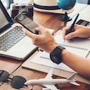 Hombres jóvenes que planean un viaje de vacaciones y buscan información o reservan un hotel en un teléfono inteligente y una computadora portátil. viajes, vacaciones de viaje,