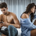 La mujer joven se siente deprimida mientras su novio está enviando mensajes de texto por teléfono celular con otra mujer.