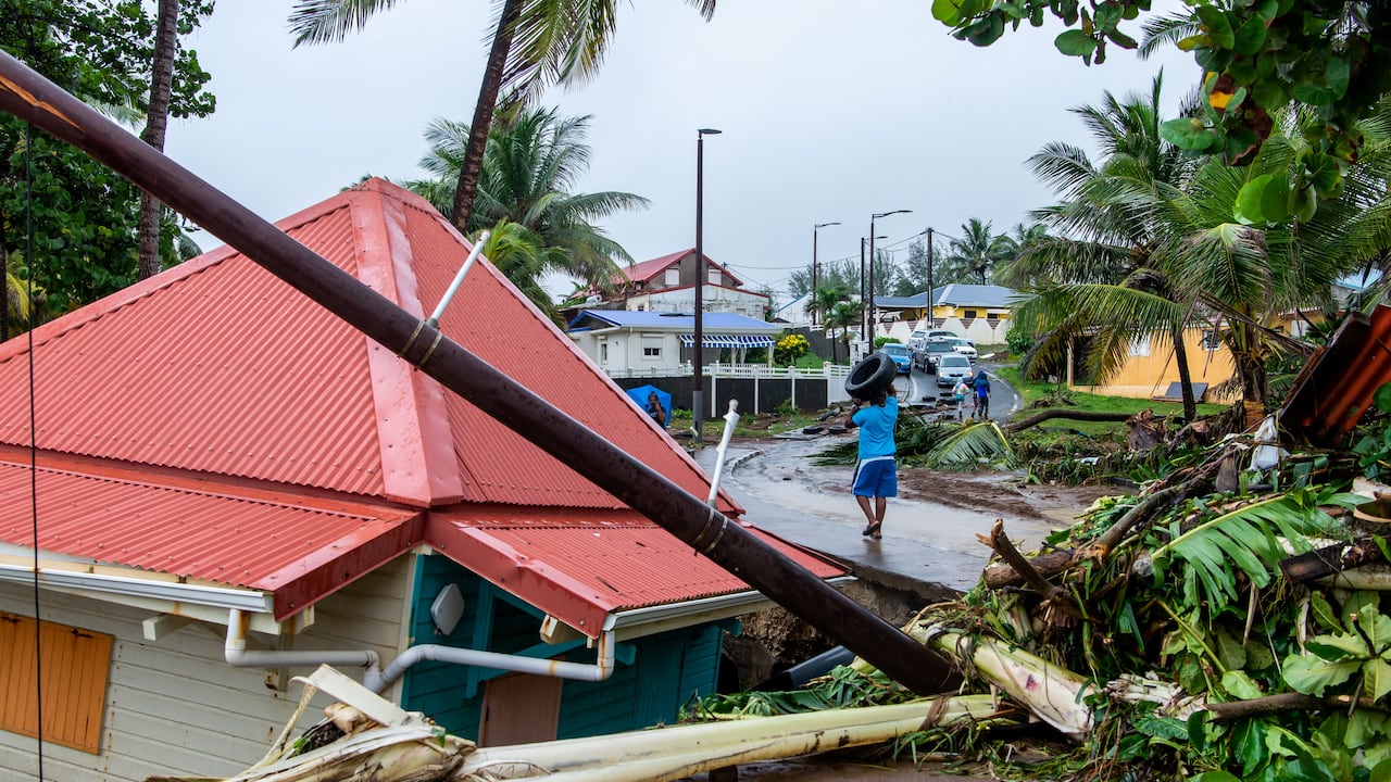 Un peatón lleva un neumático en una calle de Capesterre-Belle-Eau junto a las secuelas de la tormenta Fiona, en la isla francesa de Guadalupe, el 17 de septiembre de 2022. - La tormenta tropical Fiona abandonó el archipiélago tras provocar la muerte de un hombre, Lluvias torrenciales e inundaciones importantes. (Foto de Lara Balais / AFP)