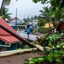 Un peatón lleva un neumático en una calle de Capesterre-Belle-Eau junto a las secuelas de la tormenta Fiona, en la isla francesa de Guadalupe, el 17 de septiembre de 2022. - La tormenta tropical Fiona abandonó el archipiélago tras provocar la muerte de un hombre, Lluvias torrenciales e inundaciones importantes. (Foto de Lara Balais / AFP)
