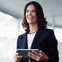 Mujer de negocios feliz mirando hacia otro lado mientras sostiene una tableta digital en la oficina