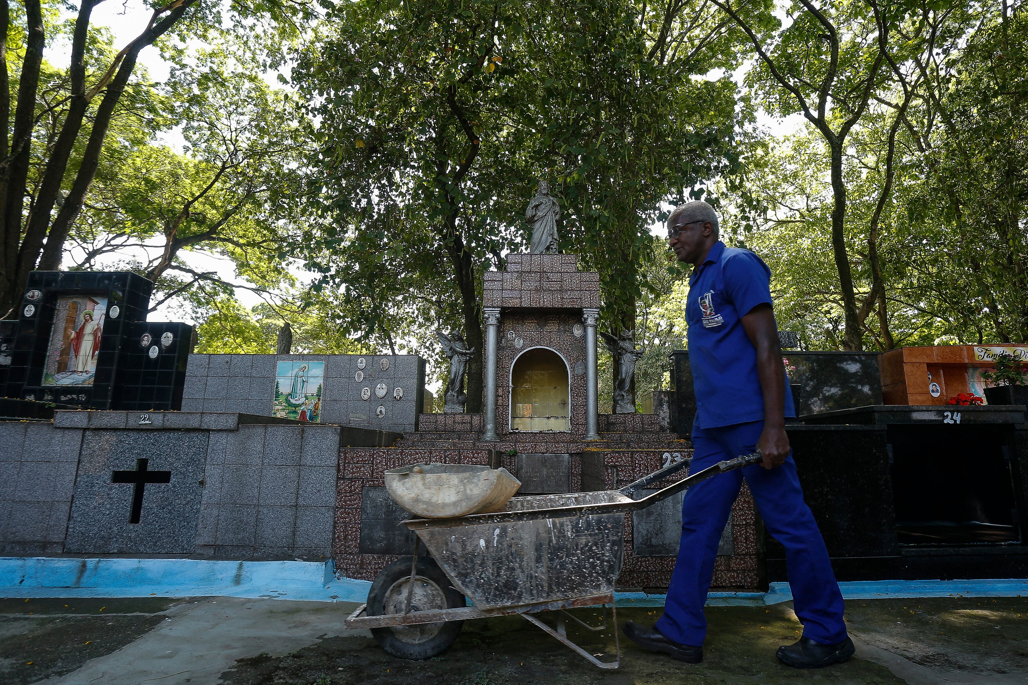 Osmair Camargo Candido, 60, known as Fininho, works as a gravedigger at a cemetery in Sao Paulo, Brazil, on September 28, 2021. - Fininho, who has worked for over 30 years as a gravedigger, is a philosophy teacher, gives vocational courses at a school, and is writing a book. (Photo by Miguel SCHINCARIOL / AFP)