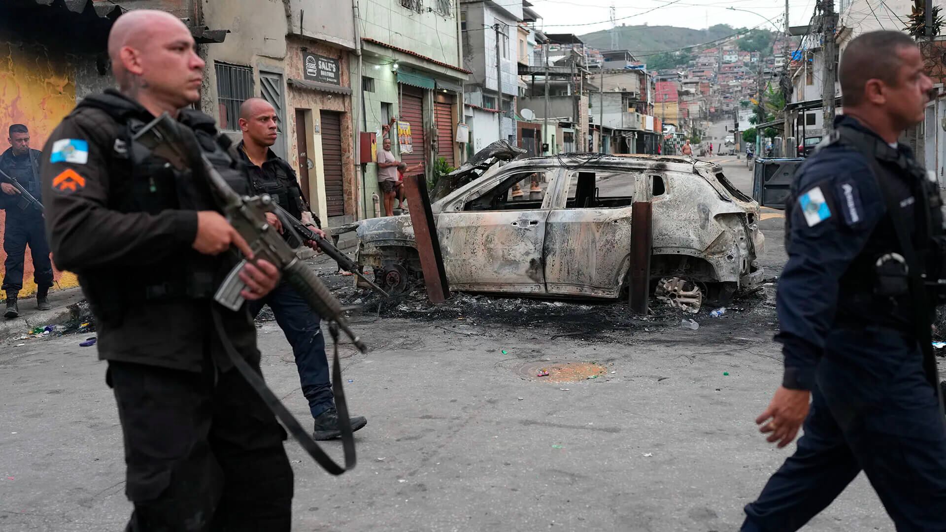 Policías pasan junto a un vehículo incendiado usado como barricada durante una operación contra presuntos narcotraficantes en el Complexo do Alemão, bastión del Comando Vermelho, en Río de Janeiro.