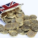 Monedas de una libra recién acuñadas saliendo del bolso con un diseño de Reino Unido.