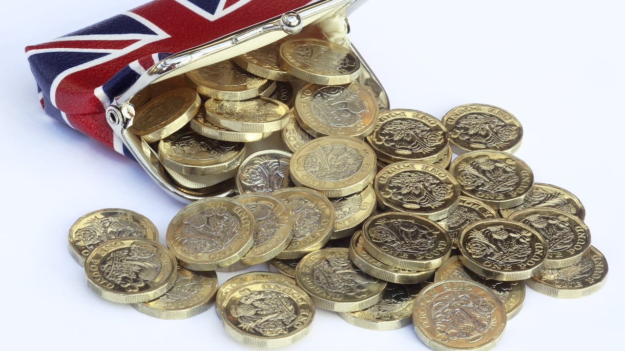 Monedas de una libra recién acuñadas saliendo del bolso con un diseño de Reino Unido.